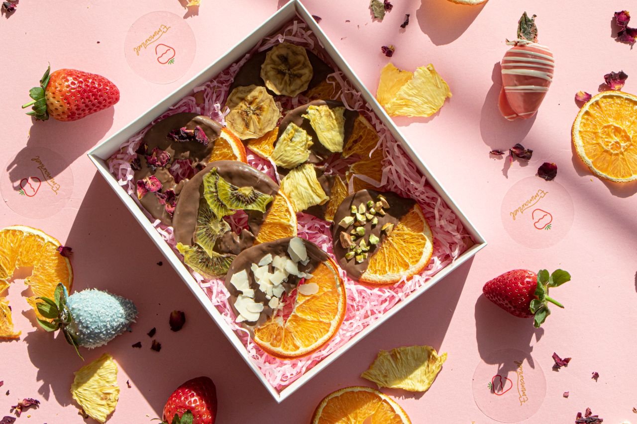 A delightful assortment of chocolate dipped dried fruits in a decorative gift box.